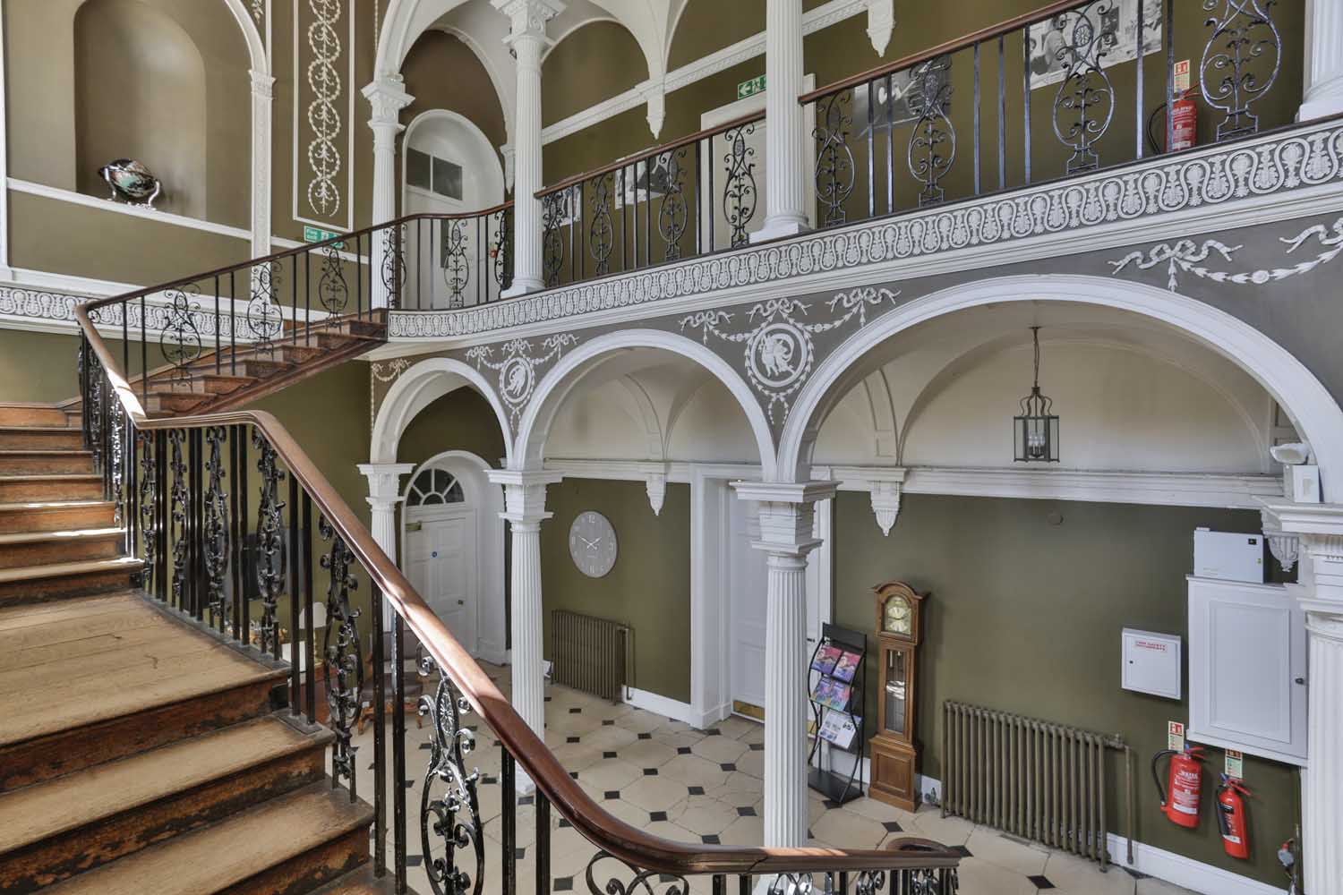 Interior view of a grand staircase and hallway in a Georgian mansion.